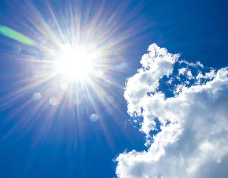 Strahlende Sonne am Himmel mit Wolken – Symbolbild für arbeitsmedizinische Vorsorge bei natürlicher optischer Strahlung und UV-Belastung im Freien