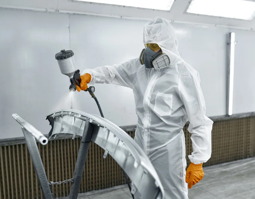 Lackierer mit Atemschutz beim Sprühen von Bauteilen – Symbolbild für G 45 Untersuchung bei Exposition gegenüber Styrol